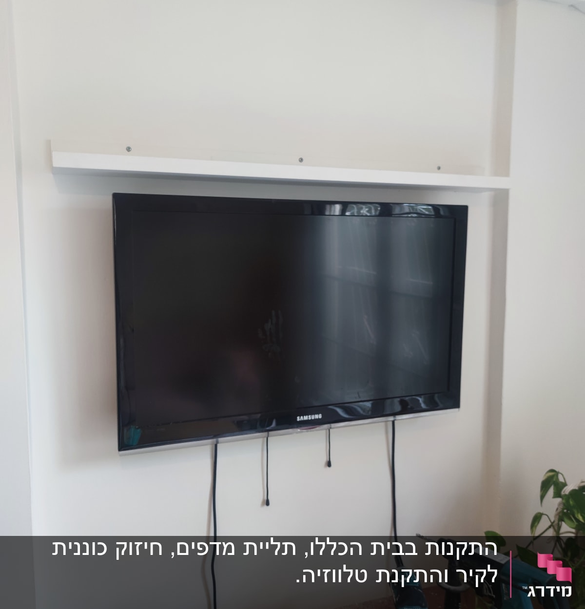 טלוויזיה תלויה על קיר עם מקדחה ומברגה על שולחן